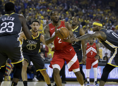 Kawhi Leonard looks to pass between Draymond Green and guard Klay Thompson.