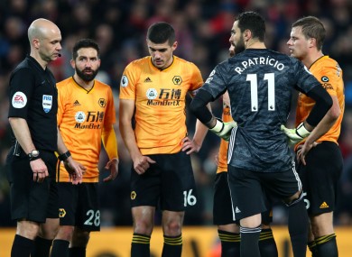 Wolves players and referee Anthony Taylor await a VAR review at Anfield.