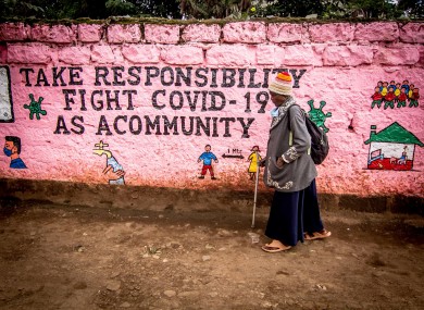 A woman walks past a wall with graffiti raising awareness about Covid-19 in Kenya.