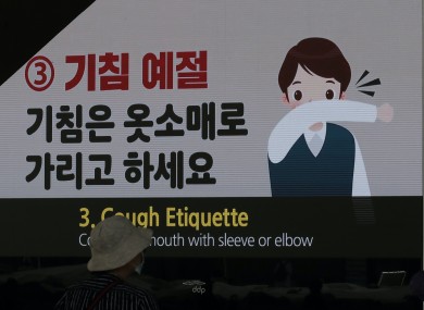 A visitor wearing a face mask walks near a screen displaying precautions against the coronavirus in Seoul, South Korea.