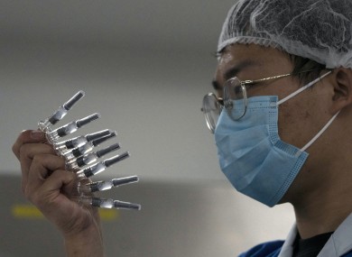 An employee manually inspects syringes of the SARS CoV-2 Vaccine
