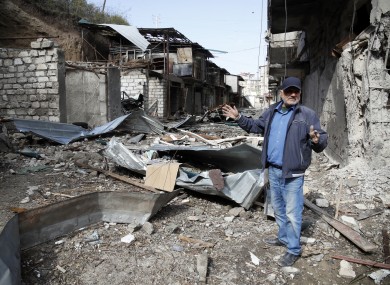 Eduard Chechyan gestures in the yard of his apartment building, destroyed by shelling by Azerbaijan's artillery
