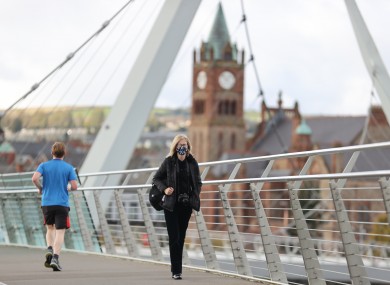 A woman walks across the Peace Bridge over the River Foyle in Derry.