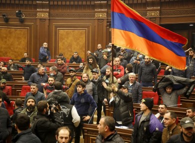 Demonstrators with an Armenian national flag protest against an agreement to halt fighting over the Nagorno-Karabakh region, at the parliamentary building in Yerevan, Armenia