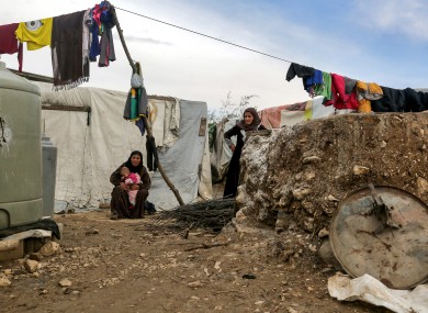 Syrian refugees sit outside their tent at al-Fares camp in Lebanon's Bekaa valley last month.
