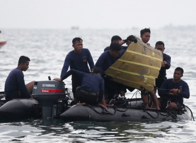 Indonesian Navy divers pull a part of an airplane out of the water during a search operation for the Sriwijaya Air passenger jet