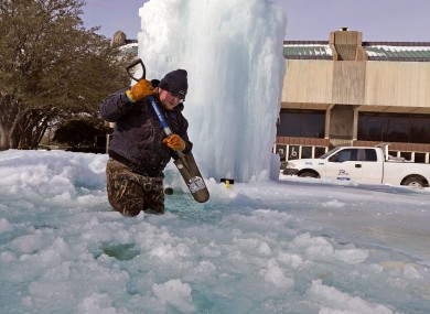 A worker breaks ice on a frozen fountain in Richardson, Texas
