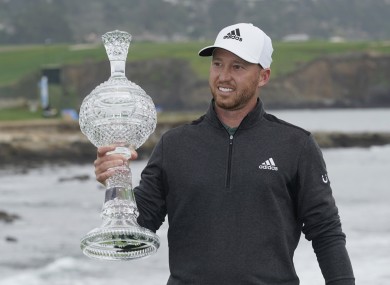 Daniel Berger holds up his trophy on the 18th green of the Pebble Beach Golf.