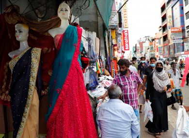 A Sri Lankan Muslim woman, right in black attire, walks in a busy street of Colombo, Sri Lanka