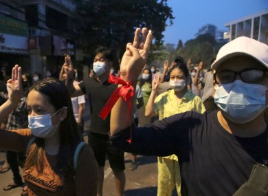 Anti-coup protesters flash three-fingered gesture, a symbol of resistance, during a rally outside their homes in downtown Yangon, Myanmar