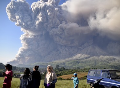 People watch as Mount Sinabung spews volcanic material during an eruption in Karo, North Sumatra