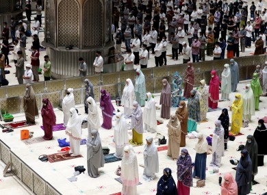 Indonesian Muslims pray spaced apart as they practice social distancing to curb the spread of the new coronavirus during an evening prayer called
