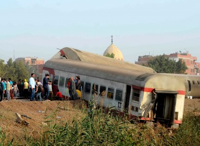 People gather at the site where a passenger train derailed in Egypt