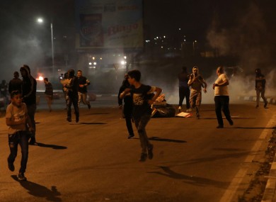 Palestinian protesters taking cover from tear gas during clashes after an anti-Israeli protest near the West Bank city of Nablus.
