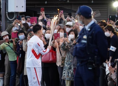 People taking pictures as a torch bearer shows the torch before a relay run in Tokyo today.