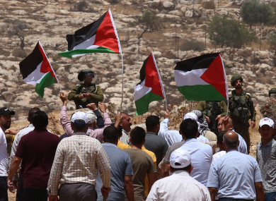 Protesters hold Palestinian flags in front of Israeli soldiers during a protest against the expansion of Jewish settlements in the village of Beit Dajan, east of the West Bank city of Nablus