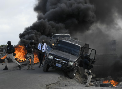 Police abandon their vehicle during a demonstration that turned violent in which protesters demanded justice for the assassinated President Jovenel Moise
